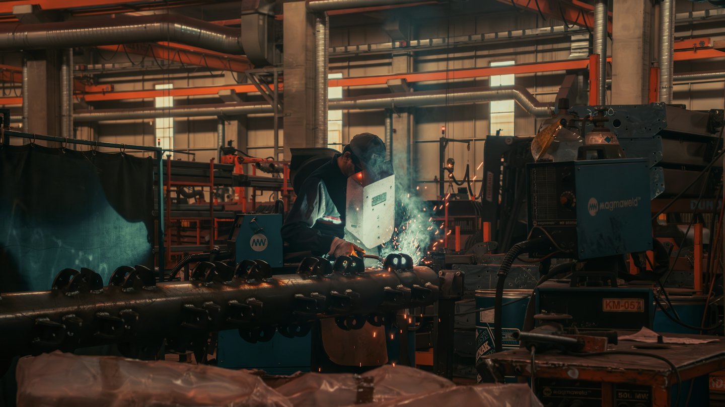 Kontakt Spawacz w kasku tworzy iskry na metalu w fabryce.